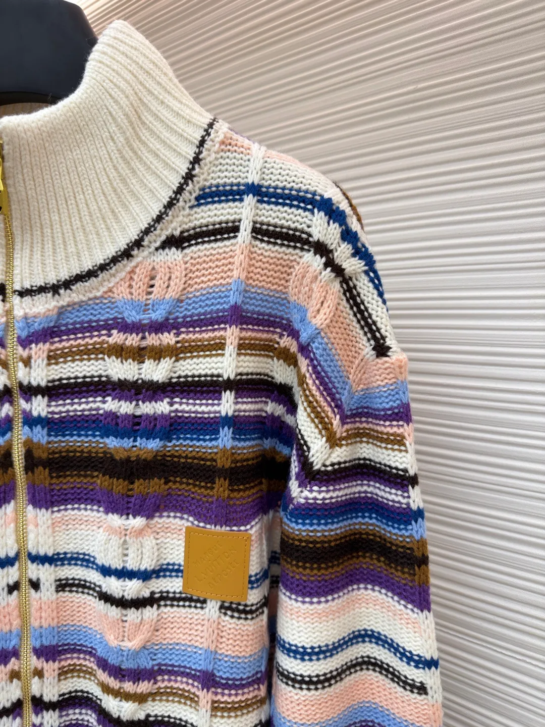 LOUIS VUITTON letter badge color block cable zipper knitted jacket ●Original version: purchased and developed by 21570 ●Item number: 1682322-C15 ●Fabric: wool blended fabric ●Technology: knitting ●Color: pattern ●Version: fitted version ●Weight: about 710 grams ●Size: S-M-L-XL ●Description: This Louis Vuitton color-blocked striped knitted cardigan is made of merino wool and cashmere blended yarn and is woven on a 12-needle coarse-gauge computerized flat knitting machine. The body is interlaced with cable knitting and plain knitting. The stripes are directly knitted with colored yarns instead of post-printing and dyeing. The ratio of colored yarns for each stripe is accurately calculated, making the color transition natural and not easy to fade. The placket is equipped with a customized brass zipper, and the zipper teeth are polished and gold-plated, which is both smooth and durable. The leather label on the left chest is fixed with first-layer calfskin through heat embossing process, and the edges are hand-polished without burrs. The neckline is designed with a high-elastic ribbed stand-up collar, which is not easily deformed after being shaped at high temperatures. The ribbed edges on the cuffs and hem are woven with double-strand yarn, which is more elastic. The shoulders are seamlessly woven with raglan sleeves to reduce the feeling of seams rubbing against the skin. The overall loose fit is combined with three-dimensional tailoring, which not only retains the soft texture of knitting, but also creates a crisp silhouette. Each piece is hand-ironed and quality-checked by brand craftsmen. The overall wiring is straight and delicate, the fabric is comfortable and soft, and the color is consistent without color difference. It can be matched with the same style to create a fashionable look and control various occasions. Customized accessories, complete with three standards, same style for men and women!